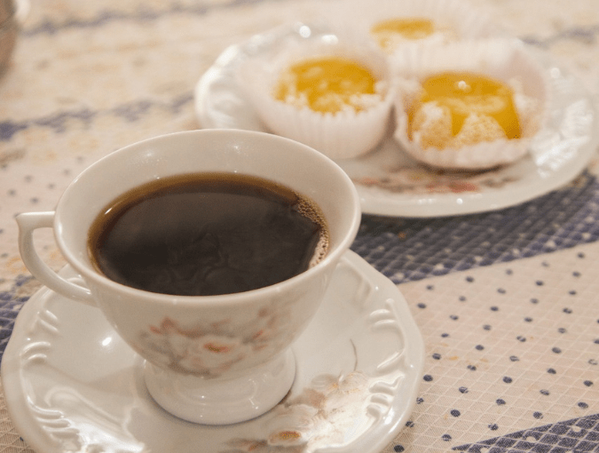 Café servido sobre a mesa com comidas na área de convivência do Hostel Parada dos Caminhantes