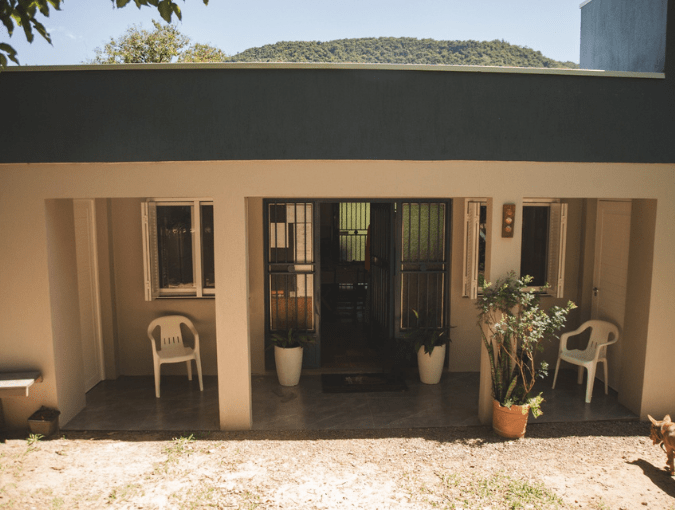 Fachada do Hostel Parada dos Caminhantes em Caravaggio-RS com área externa, cadeiras e vista para a natureza